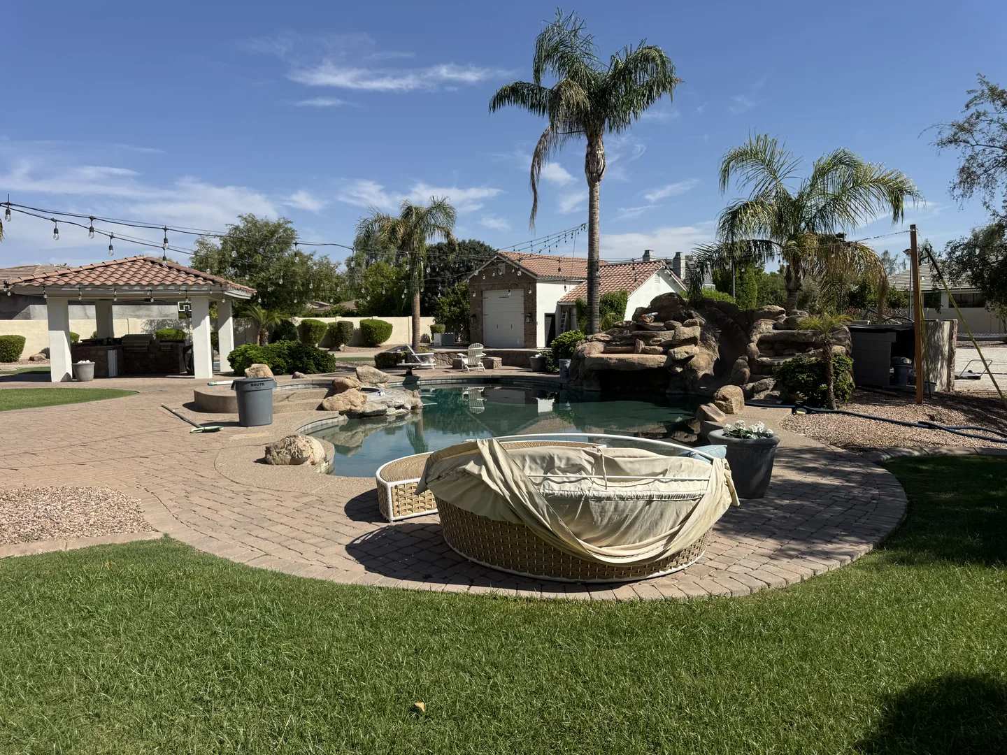 Sunny residential pool courtyard with stone paving, palms, and a central water feature