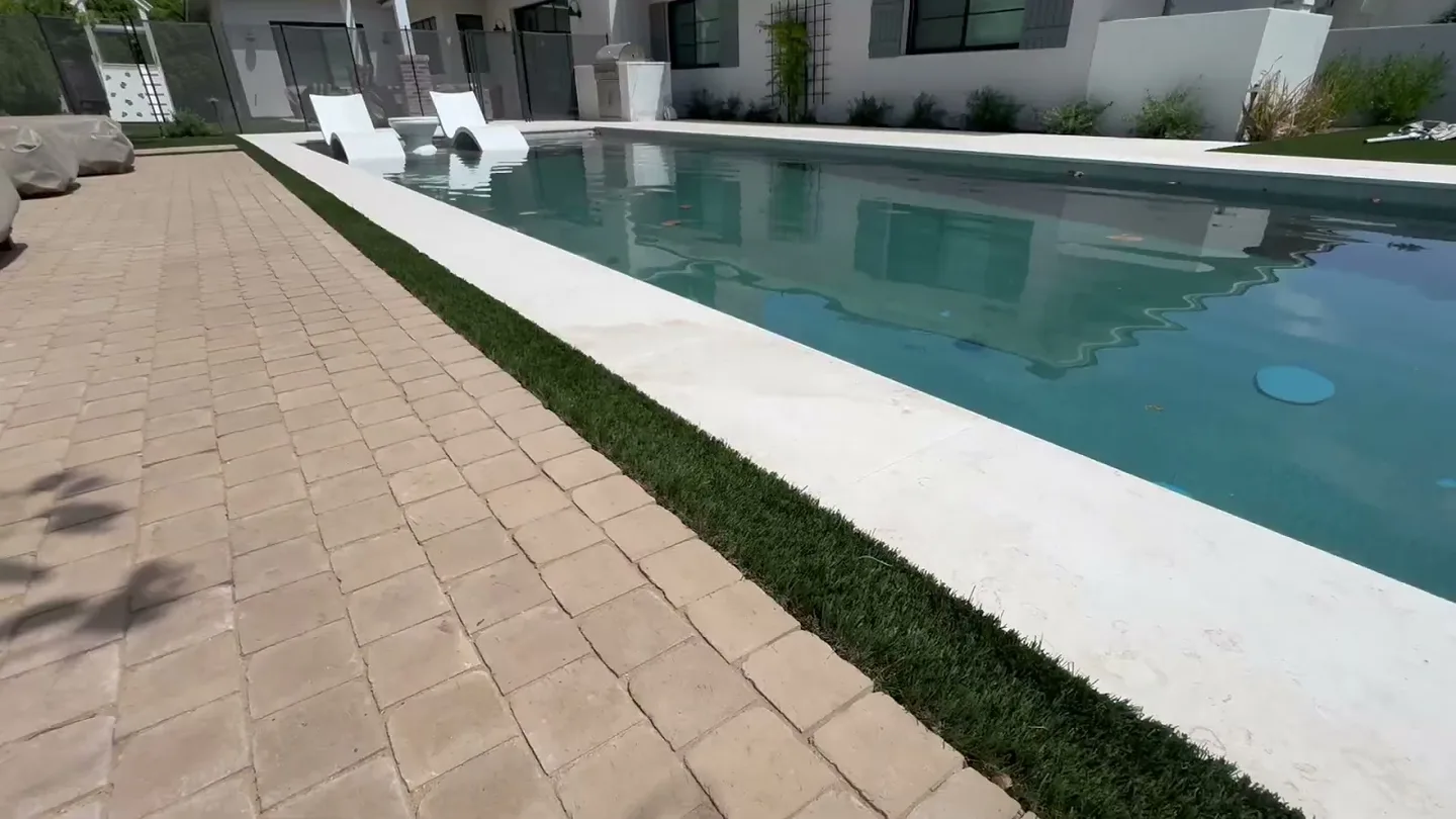Long rectangular pool beside a paved walkway and a narrow planting strip