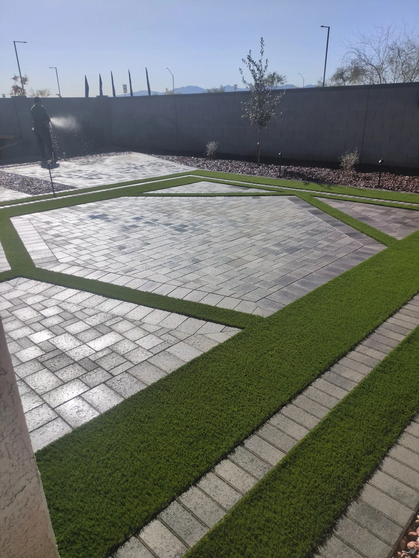 Geometric stone pavers with green turf strips in a residential yard
